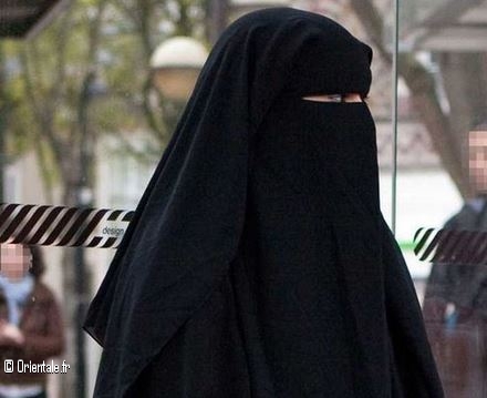 Sonia cachée en habit de musulmane pour ne pas être reconnue. Anonymisée; elle attend à un arrêt de bus
