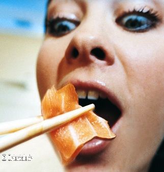 Femme mangeant un sushi au saumon Femme mangeant un sushi au saumon