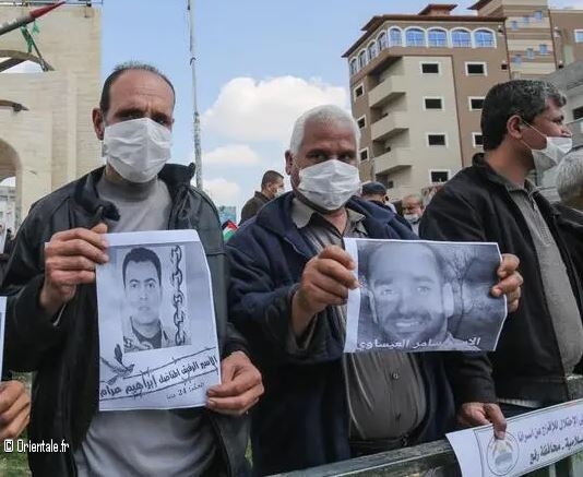 Palestiniens manifestant en portant des portraits d'hommes incarcrs en Isral