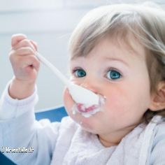 Petit bébé mangeant seul un yaourt